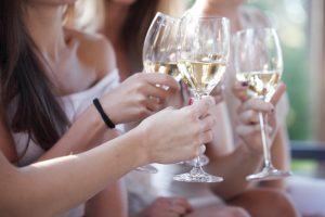 Happy female friends toasting white wine